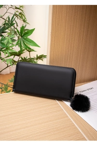Close-up of black PU leather long wallet with embroidery and fuzzy pom-pom charm