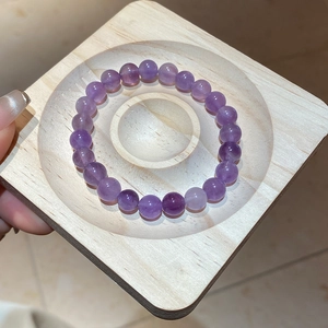 Macro detail of natural amethyst beaded bracelet with icy texture on a wooden tray