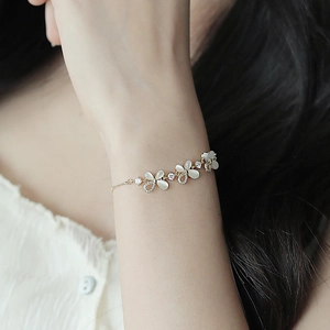 Detail of adjustable gold-tone bracelet with cat eye stone flowers and sparkling rhinestones