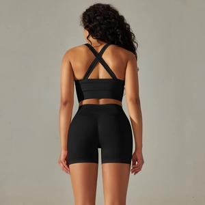 Detail of cross-back sports bra and high-waist shorts in seamless black knit fabric