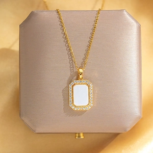 Detail of a gold square pendant with a white shell inlay and sparkling crystals