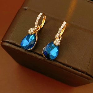 Détail macro de boucles d'oreilles vintage en or avec pierres bleues sur cuir marron
