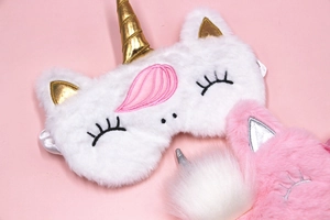 Detail view of plush unicorn sleep masks with gold horn and soft embroidery accents