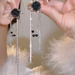 Détail de boucles d'oreilles rose noire de luxe avec longues franges argentées