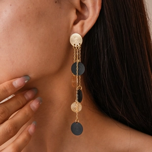 Detail of gold and black layered fringe earrings featuring textured circular metal discs