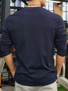 Back view of navy blue long sleeve polo shirt with waffle texture in gym setting