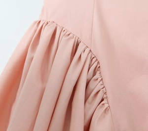 Close-up detail of pleated shoulder stitching on the pink autumn women's dress fabric