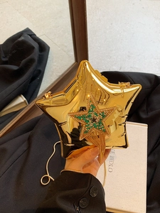 Macro detail of golden star-shaped clutch bag with sparkling rhinestone tassel and chain