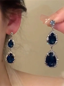 Macro detail of silver drop earrings featuring deep blue zircons with sparkling diamond halo