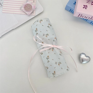 Floral fabric makeup brush roll-up bag with pink ribbon closure and blue floral pattern
