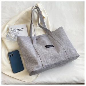 Flat lay of grey canvas tote bag showing large capacity with lifestyle items and accessories