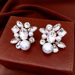Close-up of teardrop pearl earrings with rhinestones on a vintage leather box