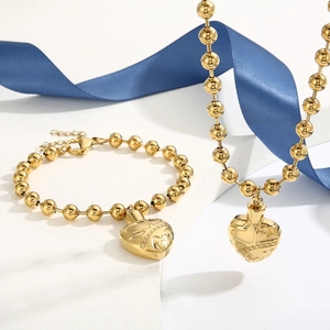 Close-up of gold stainless steel beaded necklace and bracelet set with heart urn pendant