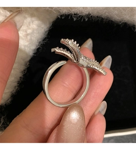 Close-up of silver bow ring with micro-paved cubic zirconia and adjustable opening