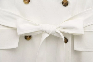 Detailed macro view of white blazer dress waist with belt bow and amber buttons