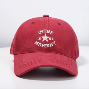 Close-up of white 'IN THE MOMENT' embroidery on red cotton baseball cap detail