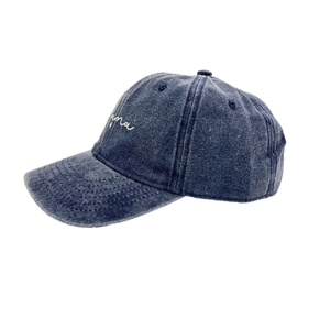 Detailed view of dark blue washed denim baseball cap with white mama script embroidery