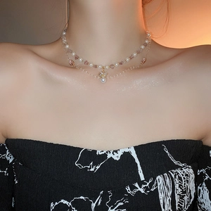 Close-up of double-layer necklace with pearls, purple crystals and golden bow pendant