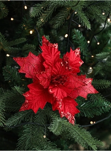 Close-up of red sequined velvet poinsettia ornament on a Christmas tree with warm lights