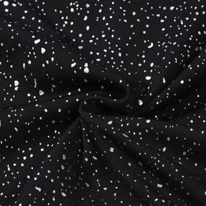 Detailed macro view of black knit fabric with metallic silver starburst foil printing