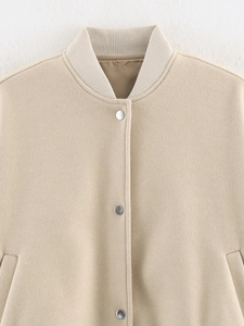 Detail of oatmeal tweed jacket featuring ribbed collar and metallic snap buttons