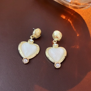 Detailed macro shot of vintage gold heart earrings with ivory resin and sparkling crystals