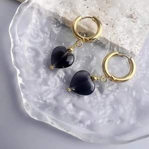 Macro detail of 18K gold-plated heart earrings with purple cat eye stones on stone texture