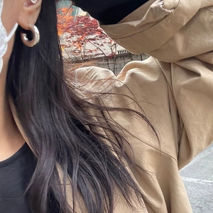 Close-up of polished silver hoop earrings worn outdoors with a minimalist design