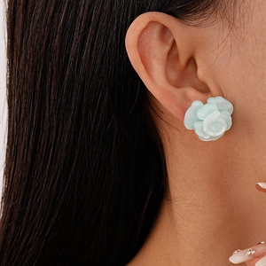 Detail of mint green resin flower earring worn on model ear with realistic petal texture