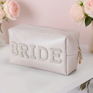 Detailed close-up of champagne BRIDE makeup bag with pearl and rhinestone letters