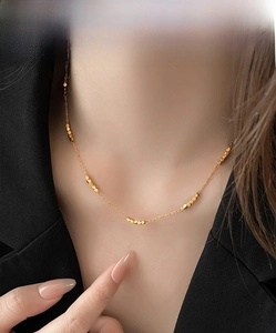 Close-up of minimalist gold beaded choker necklace on model in black suit