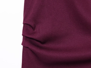 Close-up of deep wine red fabric with elegant side ruching and subtle glossy twill texture