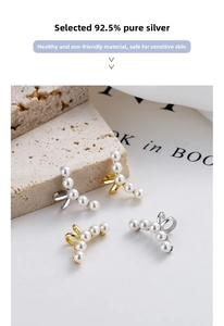 Detailed view of silver and gold pearl ear cuffs on a stone and magazine backdrop