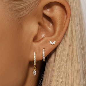Close-up of gold pavé hoop earrings and marquise stud set worn on a model's ear