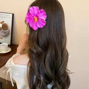 Pink hibiscus flower hair clip styled on long wavy hair for a tropical beach holiday look