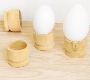Minimalist wooden egg holder set showing two white eggs and empty natural wood stands