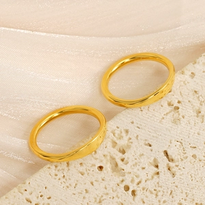 Detailed close-up of two polished 18k gold minimalist stainless steel bands on stone