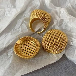 Detailansicht der goldenen hohlen Kugel-Ohrstecker und Ring auf strukturiertem Papier