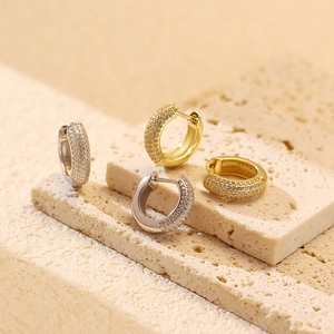 Detailed view of silver and gold pave-set hoop earrings on natural stone background