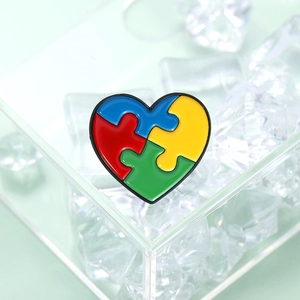 Kleurrijke hartvormige puzzelstukje speld in rood blauw groen en geel voor kleding