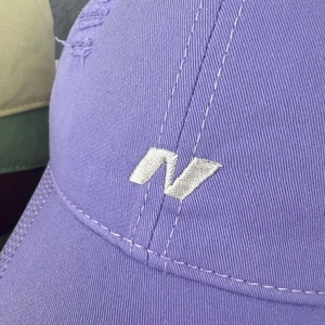 Macro shot of purple baseball cap showing detailed white N embroidery and distressed fabric
