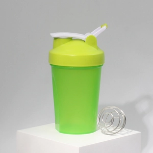 Close-up of green protein shaker bottle with measuring scale and metal mixing ball