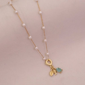 Detailed close-up of a gold necklace with white pearls, gold leaf, and sea turtle pendant