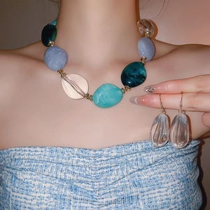 Detail of acrylic oval beaded necklace and teardrop earrings set in green and blue