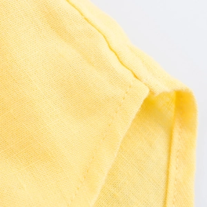 Detailed macro shot of yellow cotton linen fabric texture and high-quality stitched hem