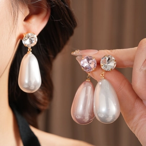 Détail de boucles d'oreilles perles en forme de goutte blanches et lavande dorées