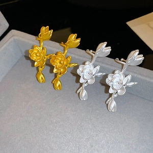 Detailed view of matte gold and silver lotus earrings on a velvet jewelry tray