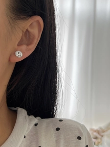 Gros plan de boucles d'oreilles smiley en argent sterling S925 portées par un mannequin