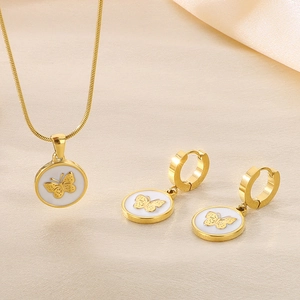 Golden butterfly necklace and earrings set with round white pendants on beige fabric