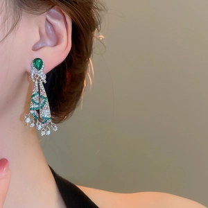 Detail of luxury drop tassel earring with green teardrop stone and bow accent